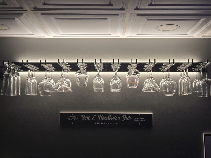 Home bar with a backlit hanging stemware rack and an illuminated sign