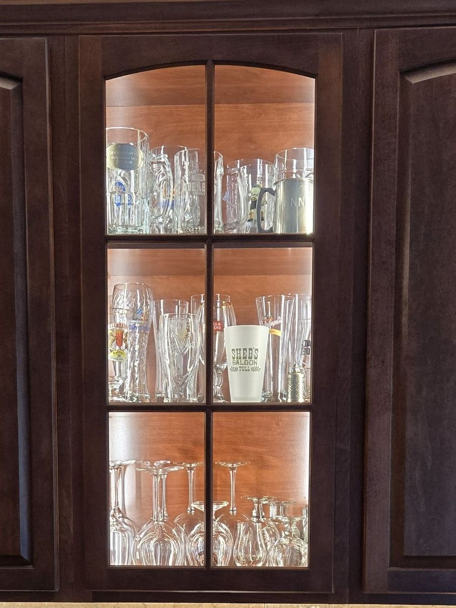 Glass-front display cabinet lit from within by warm LED accent lighting