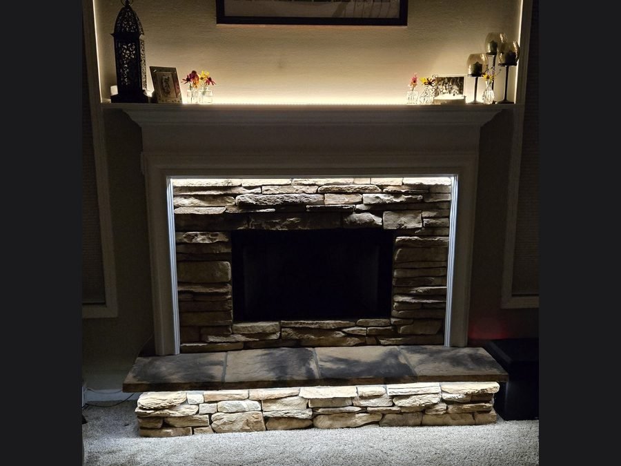 Stacked-stone fireplace with a backlit mantel shelf and glowing niche lighting above