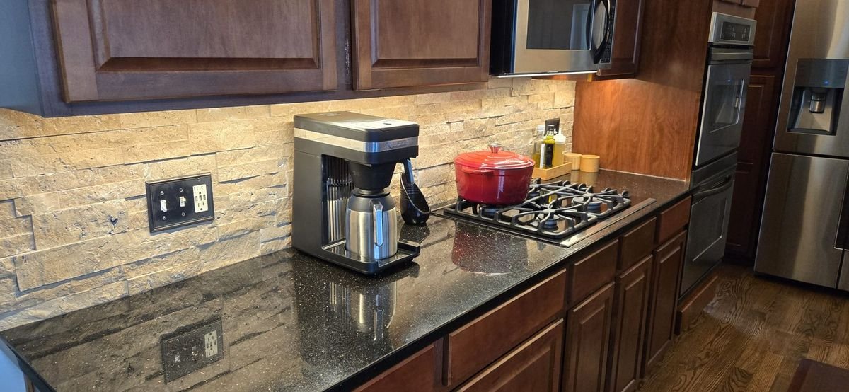 Warm accent light washing a stone backsplash behind the range