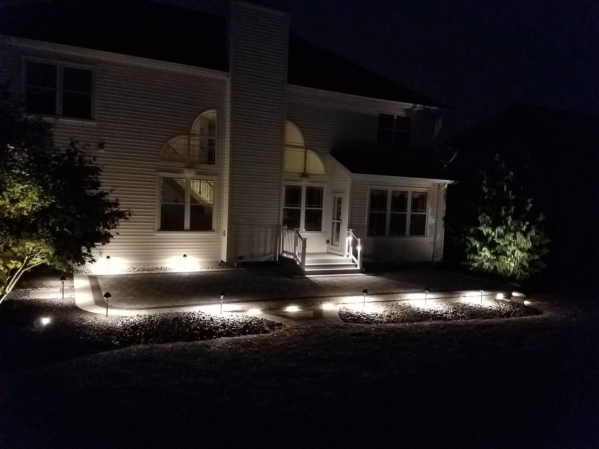 Home exterior at night with warm landscape and path lighting